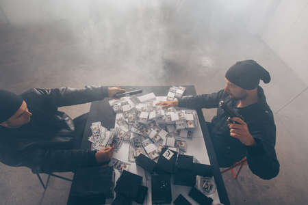 Gangsters are counting money in a smoky room, while they holding a revolverの写真素材