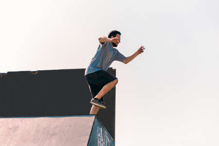 Young man in action while jumping of the wall in skateparkの写真素材