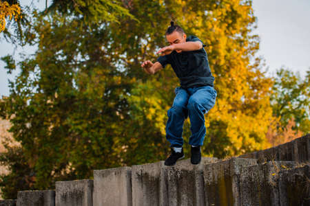 Adult man training parkour while jump over concrete wall