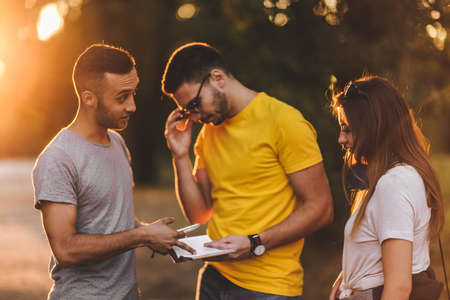 Group of friends enjoying in the park while watcing walking route in the book