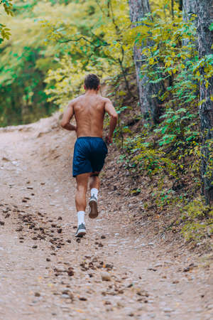 Muscular fit sport model sprinter exercising sprint on mountain road. Full body length of Caucasian modelの写真素材