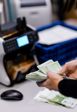 Finance person counting euro € money before loading it on to the counting machine