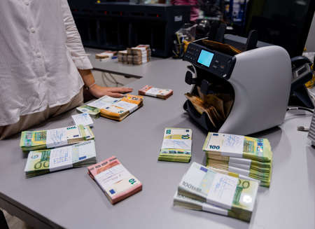 Euro â¬ banknotes stacked and binded together with currency bands in front of electronic counting machineの写真素材