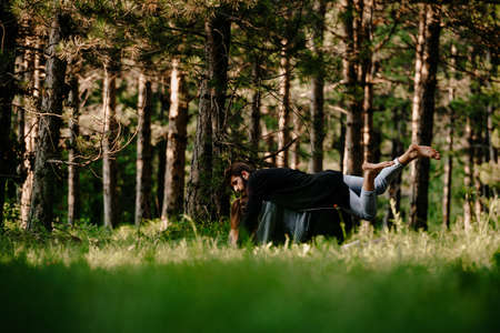 Handsome man with a beautiful young girl dancing breakdance on the green grass