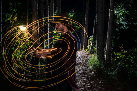 Portrait of young mysterious wizard having fun into the woodsの写真素材
