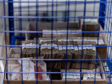 Carton boxes filled with sorted money and stored in a cage in the treasury department