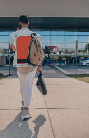 Full body portrait of man walking with luggage and phone in stationの写真素材