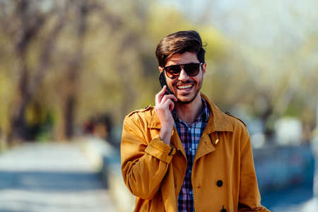 Handsome businessman is walking in the city after work while talking on mobile