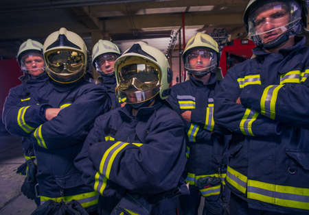 Portrait of group firefighters in front of firetruck inside the fire stationの写真素材