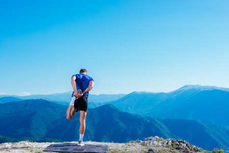 Fit male runner stretching his legs and getting ready for a long run ( workout ) early in the morning on a nice sunny day.の写真素材