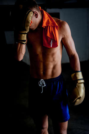 Taking time to rest. Tired young athlete in sports clothing taking break after hard trainingの写真素材