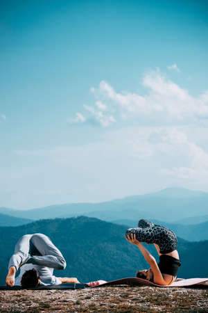 Fitness, sport, and lifestyle concept - couple making yoga exercises on mountainの写真素材