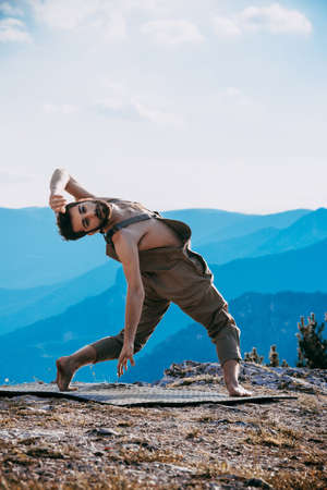Yoga practice exercise class concept.Young man doing exercises.Man practicing yoga at mountainの写真素材
