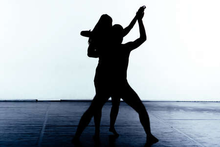Pair of young silhouette dancers practicing a contemporary ballet movementの写真素材