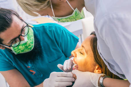 Close up portrait of a beautiful young lady sitting in the dental chair while stomatologist (...