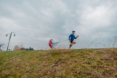 Fit mature man dressed in sportswear working out outdoors with a running parachuteの写真素材