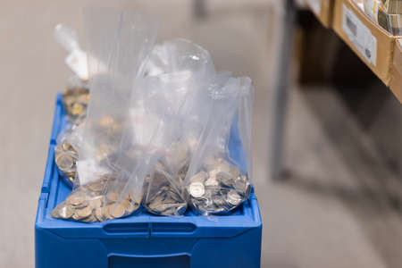 Metal coins divided in several seethrough plastic bags placed on a blue boxの写真素材