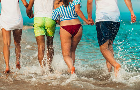 Four people having fun while jogging on the beach in the seaの写真素材