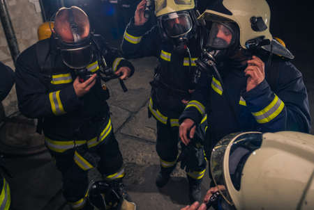 Group of firefighters standing inside the fire brigade wearing helmet and protective uniform