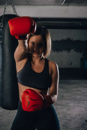 Portrait of confident young woman wearing red boxing gloves and black sports braの写真素材