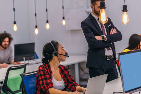 Coworkers in an office looking at a computer and talking about work