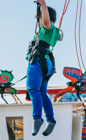 Fun loving boy jumping on the trampoline at the local carnival