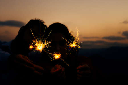 Friends enjoying in a mountain peak party and dancing with fire sparklers sticksの写真素材