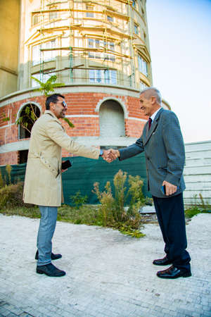 Amazing two senior buisnessmen are making a deal while doing a handshake and smiling