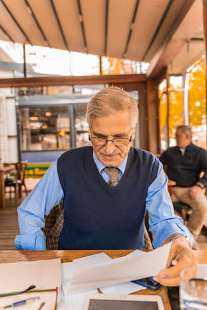 Senior and handsiome businessman is looking at the documents aloneの写真素材
