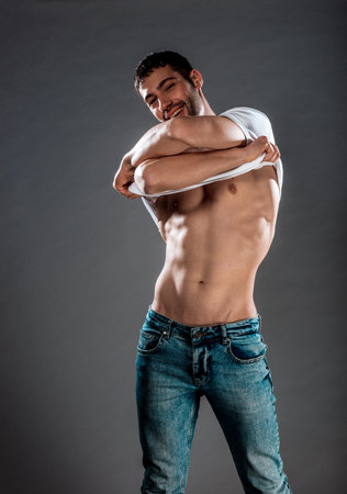 Attractive young male model posing half naked in stylish blue jeansの写真素材