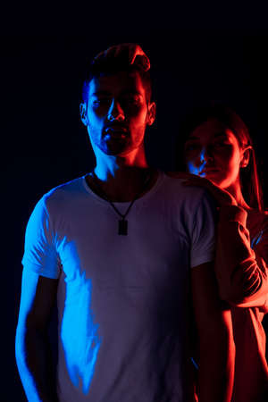 Attractive young man and woman posing against a black background