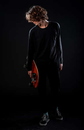 Cool skater boy dressed in blue sweater, black jeans and sneakers posingの写真素材