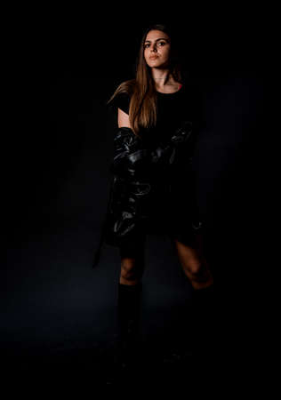 Studio body shot of a fashion female model posing in modern clothing against black backgroundの写真素材