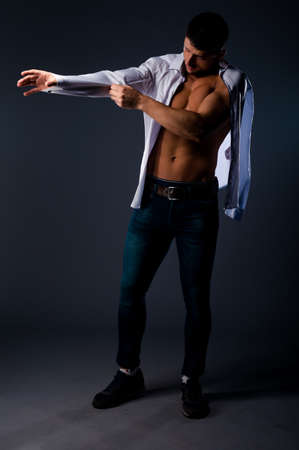 Studio fashion portrait of a handsome guy wearing blue jeans and white shirtの写真素材