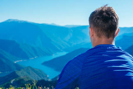 Fit male fitness trainer chilling on top of a mountain on a sunny day.