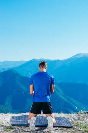 Strong male athlete doing plank while exercising his abs on top of a mountain on a sunny day.の写真素材