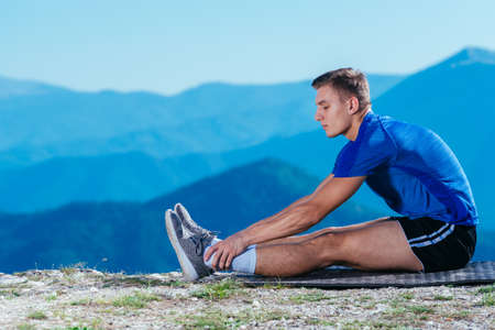Athlete, long distance runner stretching his legs in nature.Getting ready for a run.