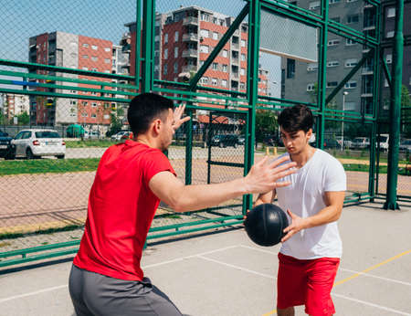 Two strong male basketball players play ball out doors fighting for a clean shot for three on a nice...