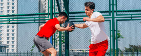 Basketball players playing ball(pushing, dribbling) on an urban basketball ground while the white...