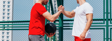 Basketball players playing ball(pushing, dribbling) on an urban basketball ground while the white skyscrapers nearly touch the blue sky.の写真素材