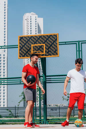 Two basketball players having some rest sitting on the court after an exhausting basketball game.