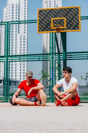 Two basketball players having some rest sitting on the court after an exhausting basketball game.の写真素材