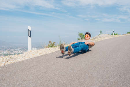 Urban cool longboarder preparing for a downhill ride(slide) doing few stunts and trick on his longboard, grabbing the board while riding.の写真素材