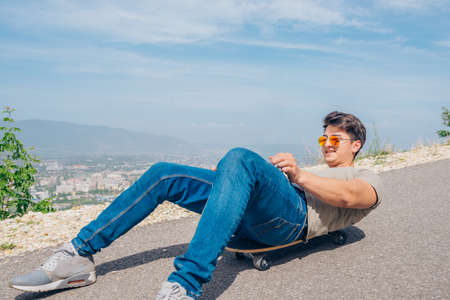 Urban cool longboarder preparing for a downhill ride(slide) doing few stunts and trick on his longboard, grabbing the board while riding.の写真素材
