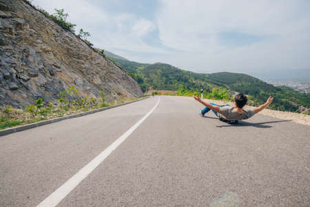 Urban cool longboarder preparing for a downhill ride(slide) doing few stunts and trick on his longboard, grabbing the board while riding.の写真素材