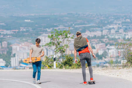 Tall athlete riding his longboard fast and steady downhill while wearing red t-shirt and black jeans.の写真素材