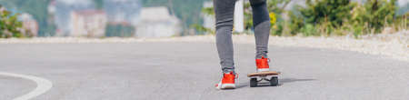 Tall athlete riding his longboard fast and steady downhill while wearing red t-shirt and black jeans.の写真素材