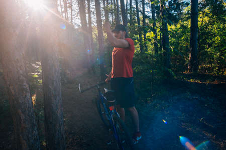 Portrait of a handsome mountain biker drinking water while wearing his baseball cap (hat).