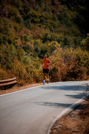 Jogging male fitness model working out training for marathon on forest road in amazing nature...