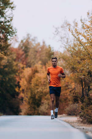 Fitness male sport fitness model sprinting outdoors on mountain pathの写真素材